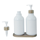 Bottiglia bianca della lozione del bagno con la pompa di bambù per il lavaggio del corpo e dello sciampo