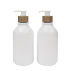 Bottiglia bianca della lozione del bagno con la pompa di bambù per il lavaggio del corpo e dello sciampo